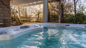 A hot tub with a stone wall and a pergola. - The Cottage at Capitol Hill by Avantstay Group Retreat + Yard Walk to Paso (Paso Robles)