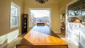 A dining room with a long wooden table, a chandelier, and a view through a window. - The Cottage at Capitol Hill by Avantstay Group Retreat + Yard Walk to Paso (Paso Robles)