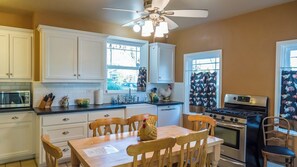 A kitchen with white cabinets, a stove, a microwave, and a ceiling fan. - The Cottage at Capitol Hill by Avantstay Group Retreat + Yard Walk to Paso (Paso Robles)