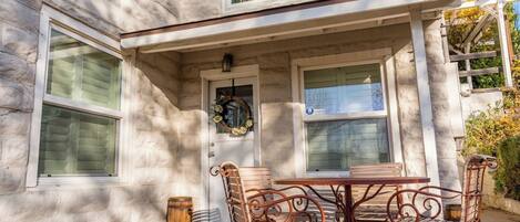 A stone building with a covered patio, a table with chairs, and a wreath on the door.