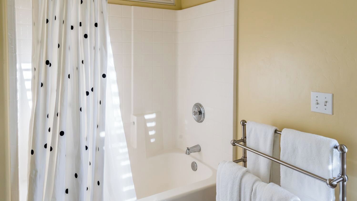 A bathroom with a bathtub, a shower curtain, and a towel rack.