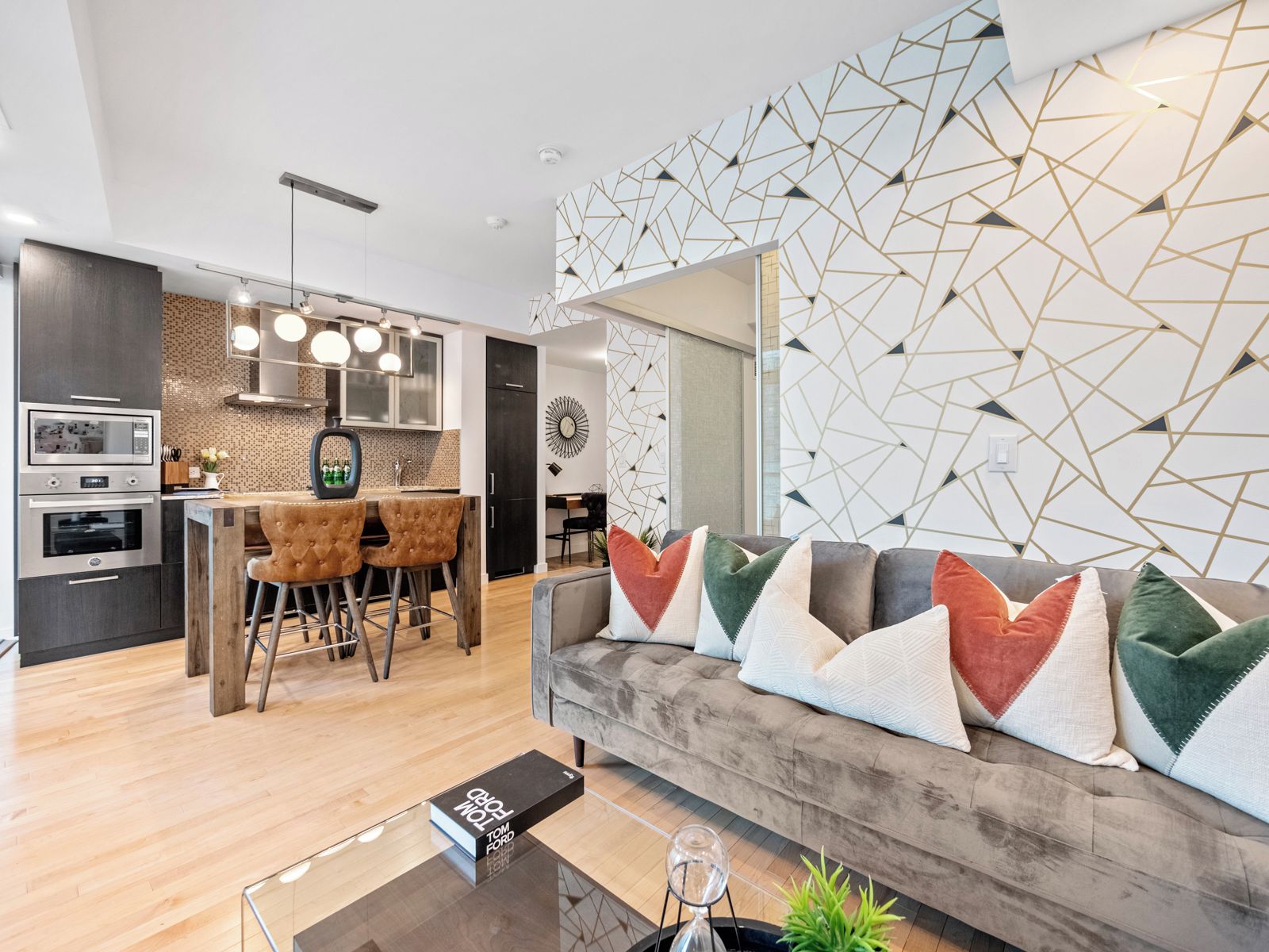 Een moderne woonkamer met een bank, een bijzettafeltje en een eethoek met een bar.