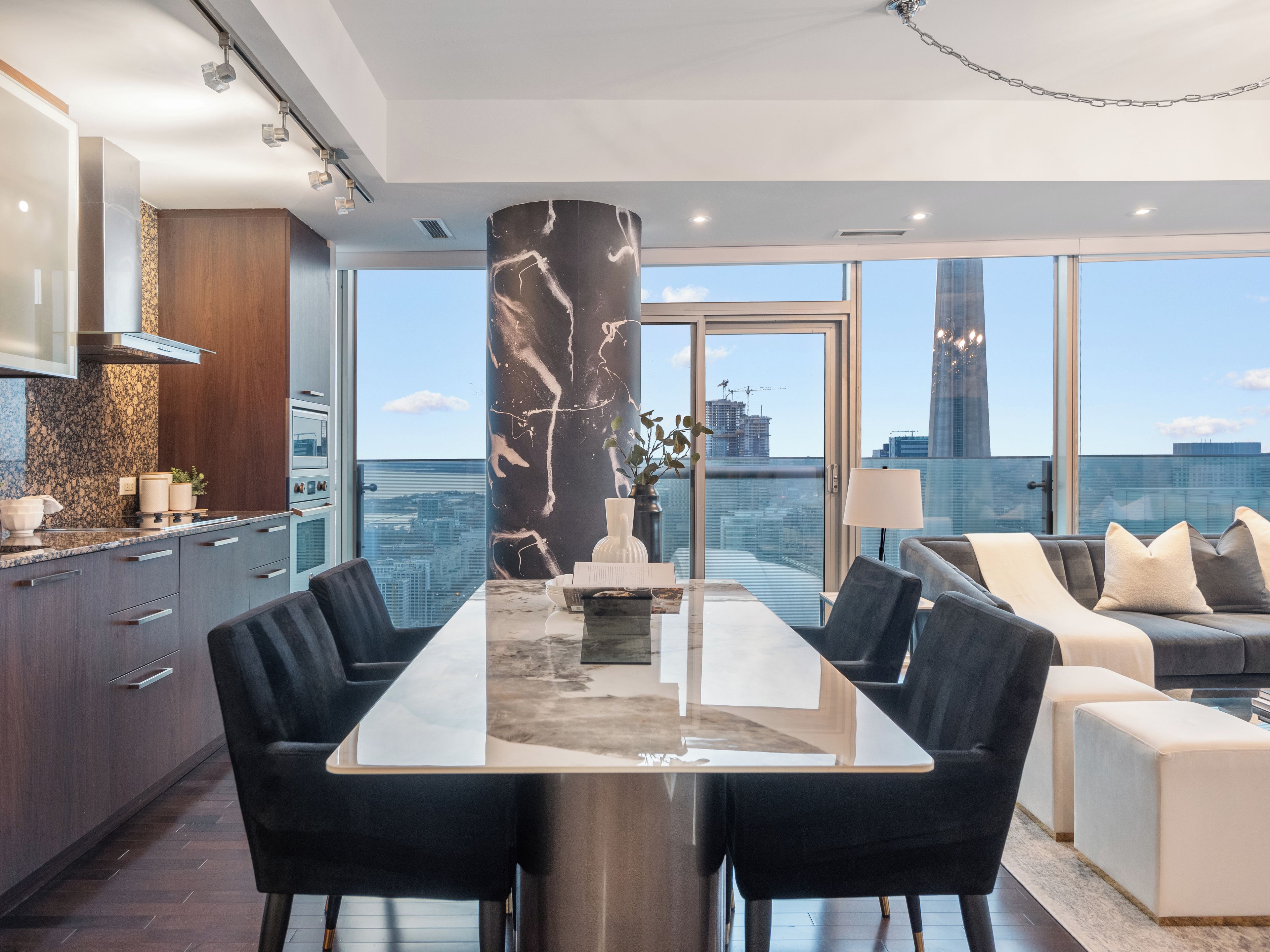 A modern interior with a dining area, kitchen, and seating space with a city view.