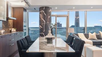 A modern interior with a dining area, kitchen, and seating space with a city view.