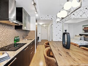 Una cocina moderna con salpicadero de azulejos, estufa integrada y comedor con mesa de madera y sillas de cuero.