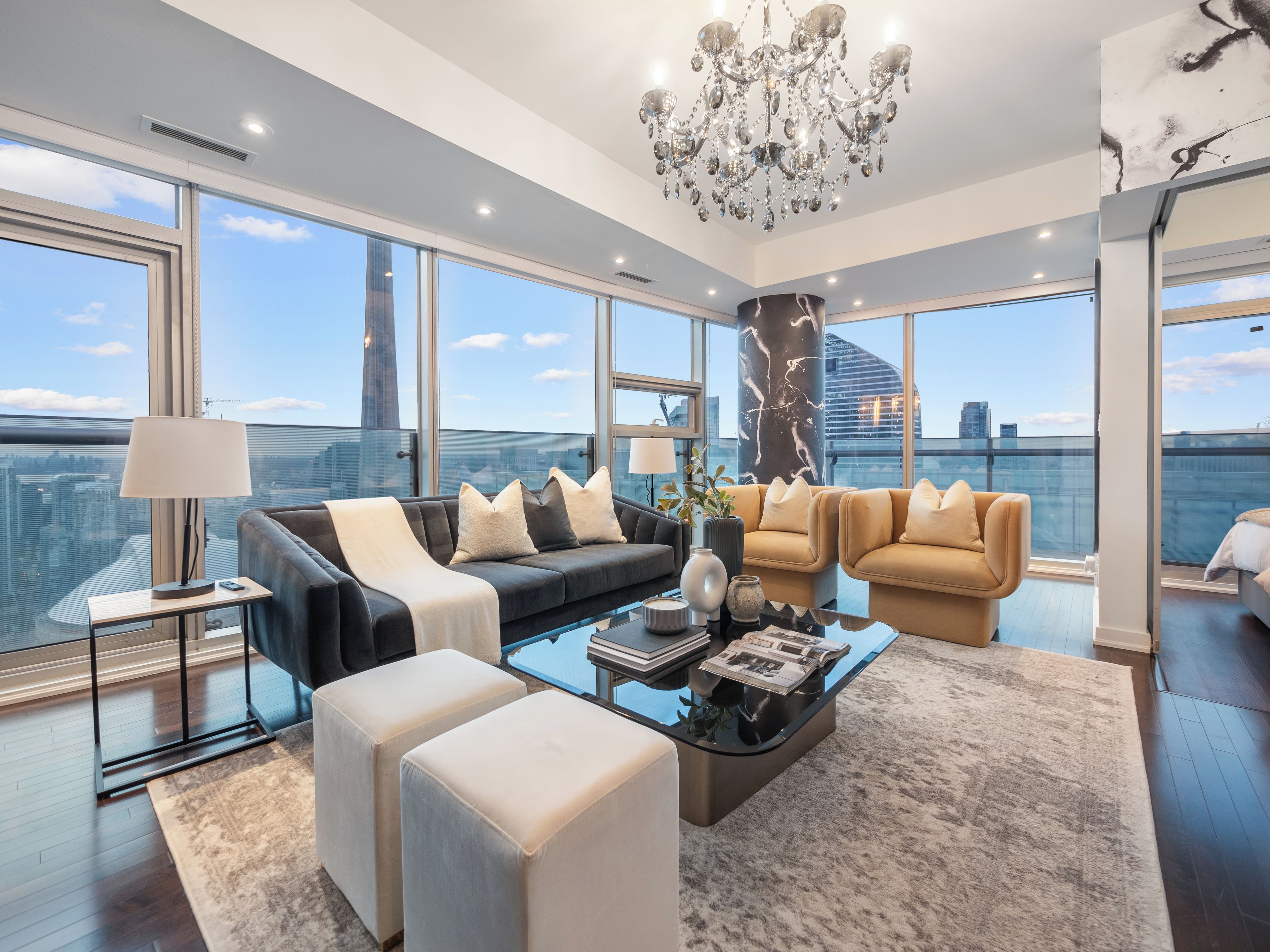 A modern living room with large windows, a chandelier, and a city view.