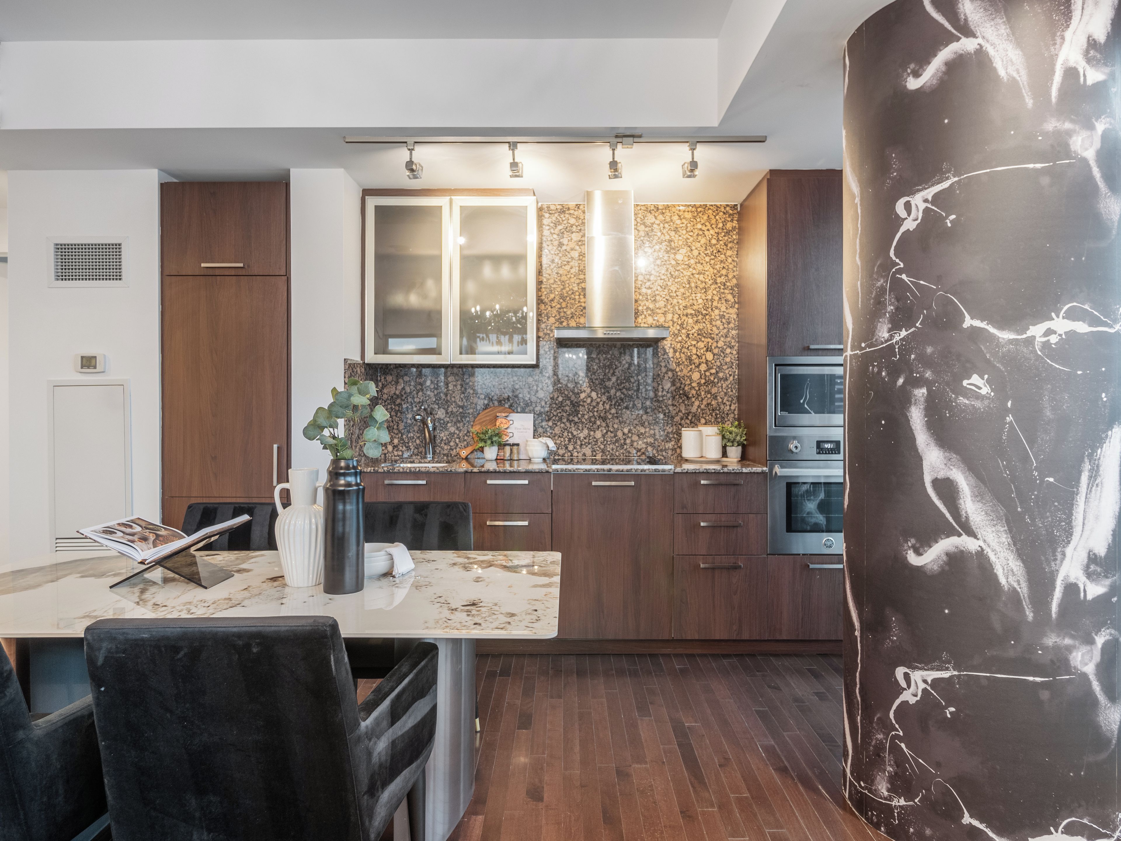 Une cuisine moderne avec des meubles en bois foncé, un plan de travail en granit et des appareils électroménagers en acier inoxydable.