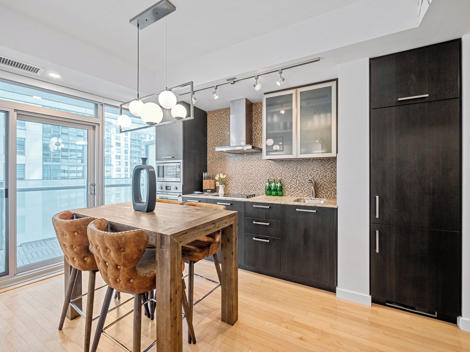Een moderne keuken met een eethoek, met een houten tafel, barstoelen en een groot raam met uitzicht over de stad.