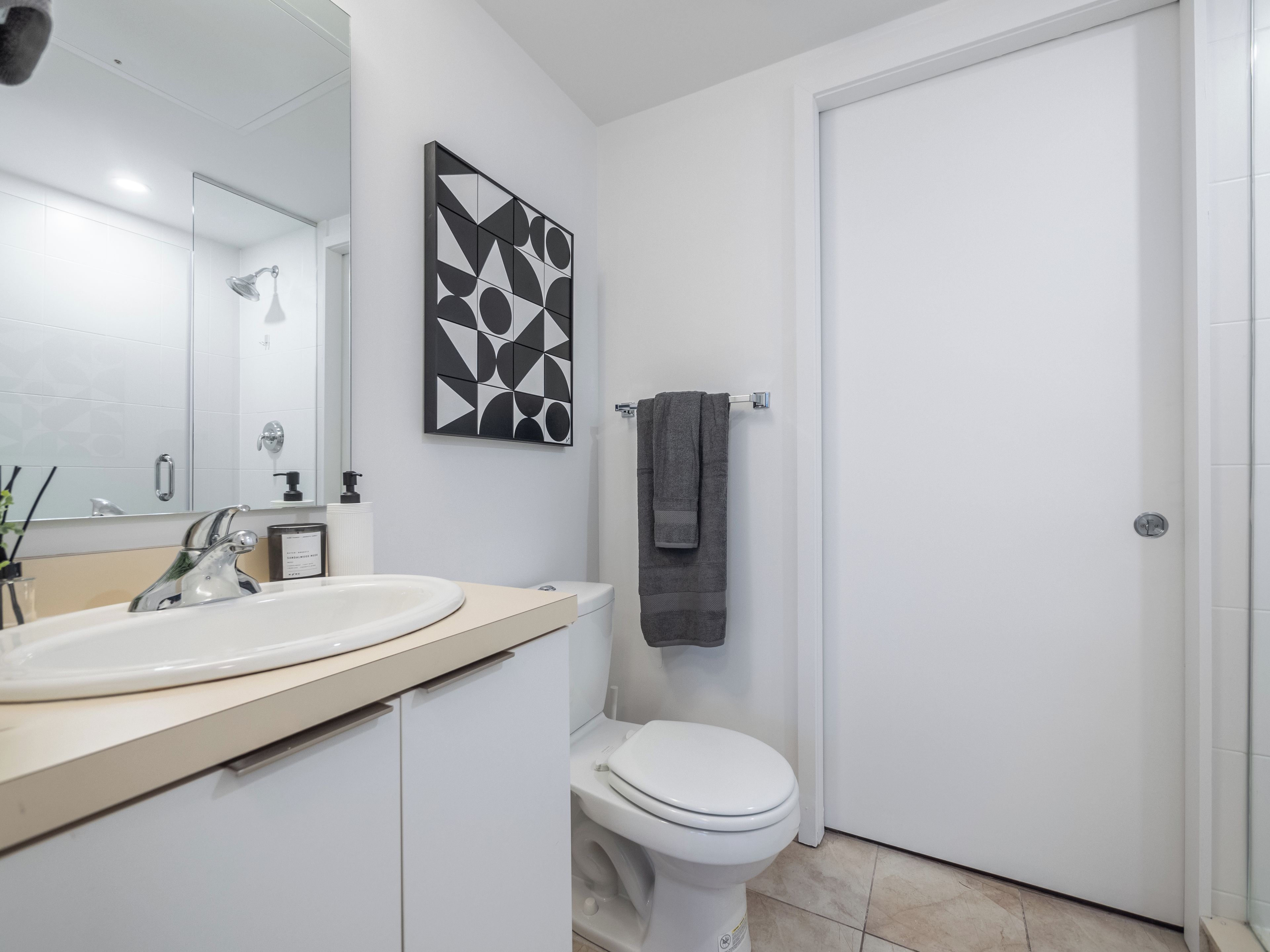 A modern bathroom with a white sink, toilet, and shower.