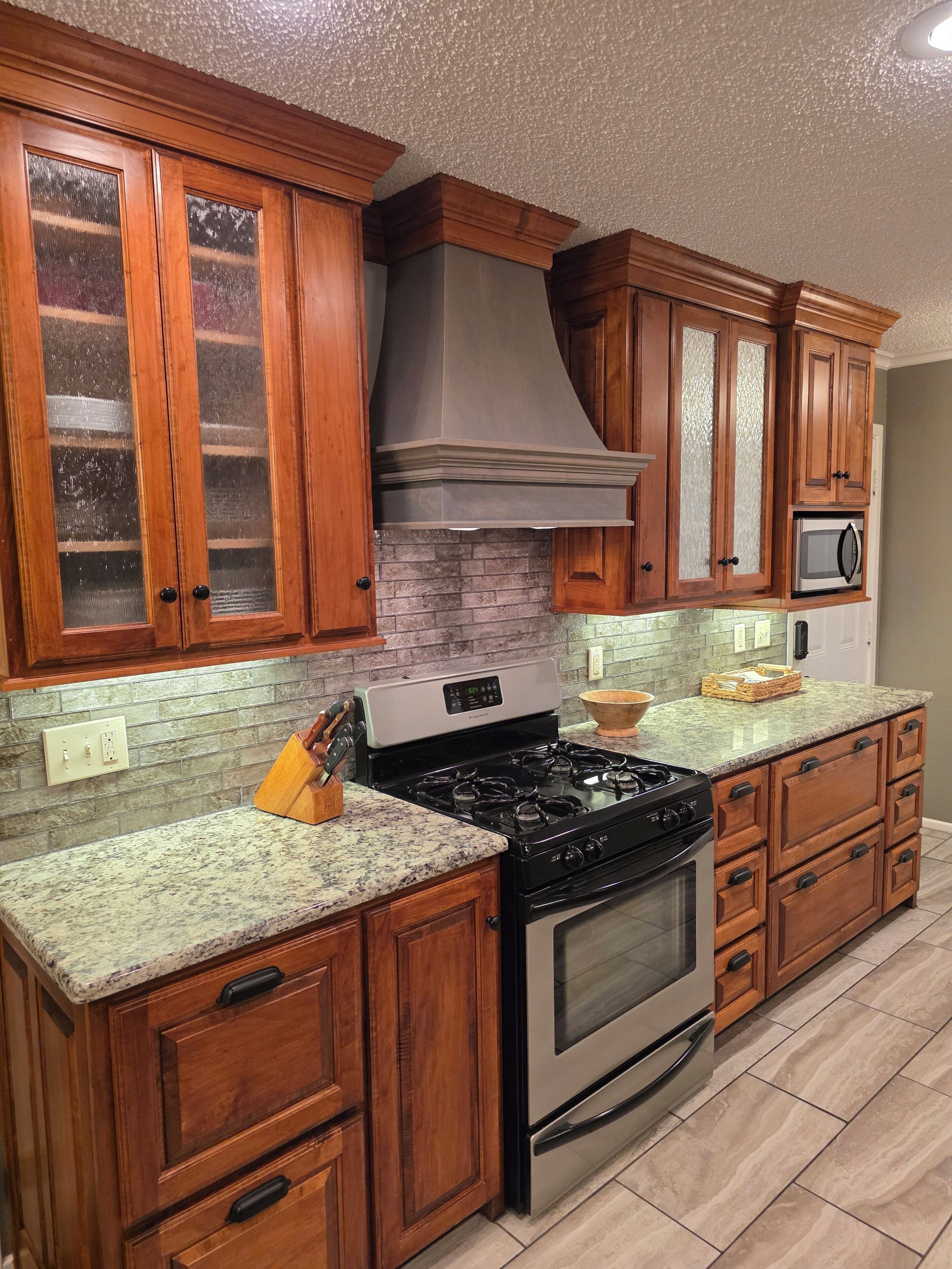 A kitchen with wooden cabinets, a stainless steel stove, and a microwave.