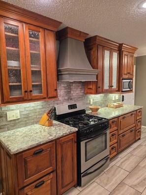 Una cocina con armarios de madera, estufa de acero inoxidable y un microondas.