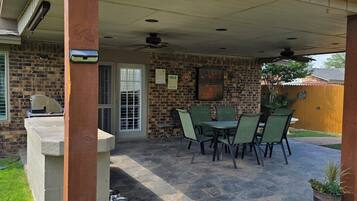 A covered patio with a brick wall, a grill, and outdoor seating.