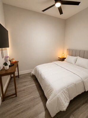 A bedroom with a bed, a nightstand, a desk, a ceiling fan, and a wall-mounted TV. - Modern Retreat / Private Entrance + Free Parking (West Park)