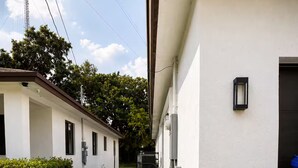 Un bâtiment moderne avec un trottoir dallé menant à l’entrée, entouré de pelouse bien entretenue et de quelques plantes en pot.