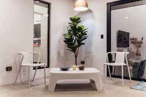 Ein modernes Interieur mit einem weißen Tisch, zwei weißen Stühlen, einer Topfpflanze und einer Pendelleuchte.