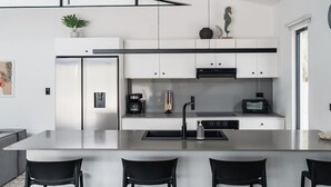 Eine moderne Küche mit einer zentralen Kochinsel, schwarzen Stühlen und einer Kaffeemaschine.