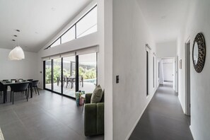 En modern inredning med ett matområde, en soffa och en hall som leder till ett annat rum.