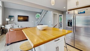 Una cocina moderna con una isla central, electrodomésticos de acero inoxidable y una escalera que conduce a otro nivel.