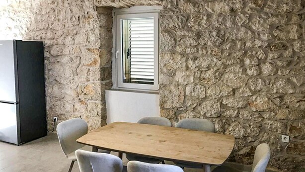 A stone-walled room with a wooden table and four chairs. - Lovely home in Zaostrog with house sea view (Zaostrog)
