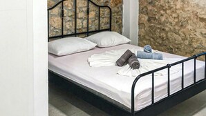 A bed with a stone wall background, a metal headboard, and white linens. - Lovely home in Zaostrog with house sea view (Zaostrog)