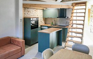 Eine kompakte Küche mit Steinwand, Einbauofen und Kücheninsel aus Holz mit Spüle.