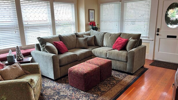 A living room with a sectional sofa, ottoman, and a patterned rug. - Poe House by Avantstay 1916 Craftsman Downtown Paso (Paso Robles)