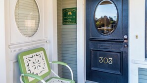 A black door with the number 303, a green chair with a decorative pattern, and a sign for the Mary Agnes Poe Historical Society. - Poe House by Avantstay 1916 Craftsman Downtown Paso (Paso Robles)