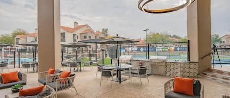 An outdoor patio area with seating, tables, and a barbecue grill.