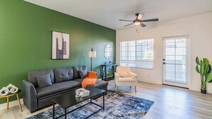 A living room with a green wall, a gray sofa, a coffee table, and a ceiling fan. - Princess Dr Retreat Pool Balcony Parking WD WiFi (Scottsdale)