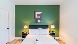 A hotel room with a large bed, two bedside tables, a green accent wall, and a modern abstract artwork. - Princess Dr Retreat Pool Balcony Parking WD WiFi (Scottsdale)