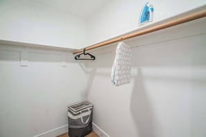 A laundry area with a hanging rack, a small trash bin, and a wall-mounted iron. - Desert Oasis Near TPC Poo Balcony Parking WD (Scottsdale)