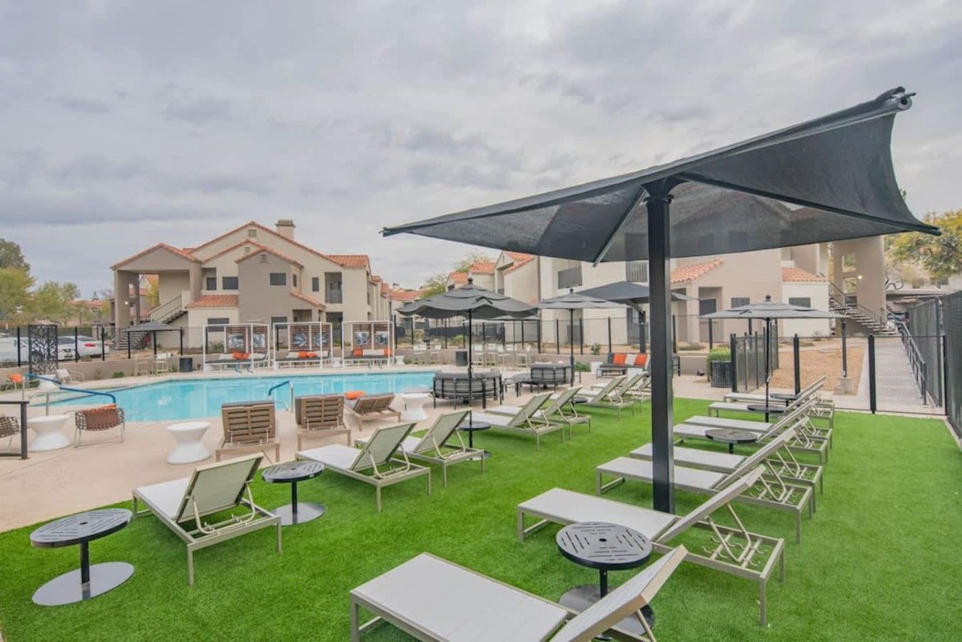 Un espace aménagé au bord de la piscine, avec des chaises longues, une piscine et un bâtiment en arrière-plan.