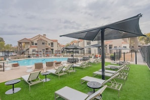 A poolside area with lounge chairs, a pool, and a building in the background. - Near TPC Golf Balcony Pool Parking WD WiFi (Scottsdale)
