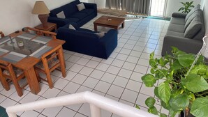 A living room with a blue sofa, a wooden coffee table, a grey sofa, and a TV mounted on the wall. - Monthly Beach House Rental in Manzanillo, Mexico – Perfect for Snowbirds (Manzanillo)