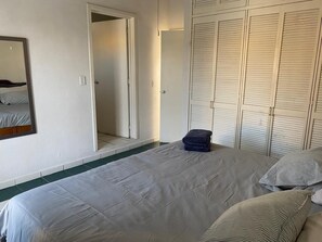 Une chambre à coucher comprenant un lit, un miroir, une armoire et une porte donnant sur une autre pièce.