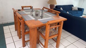 A dining table with chairs, a blue sofa, and a lamp in a room with white walls and tiled flooring. - Monthly Beach House Rental in Manzanillo, Mexico – Perfect for Snowbirds (Manzanillo)