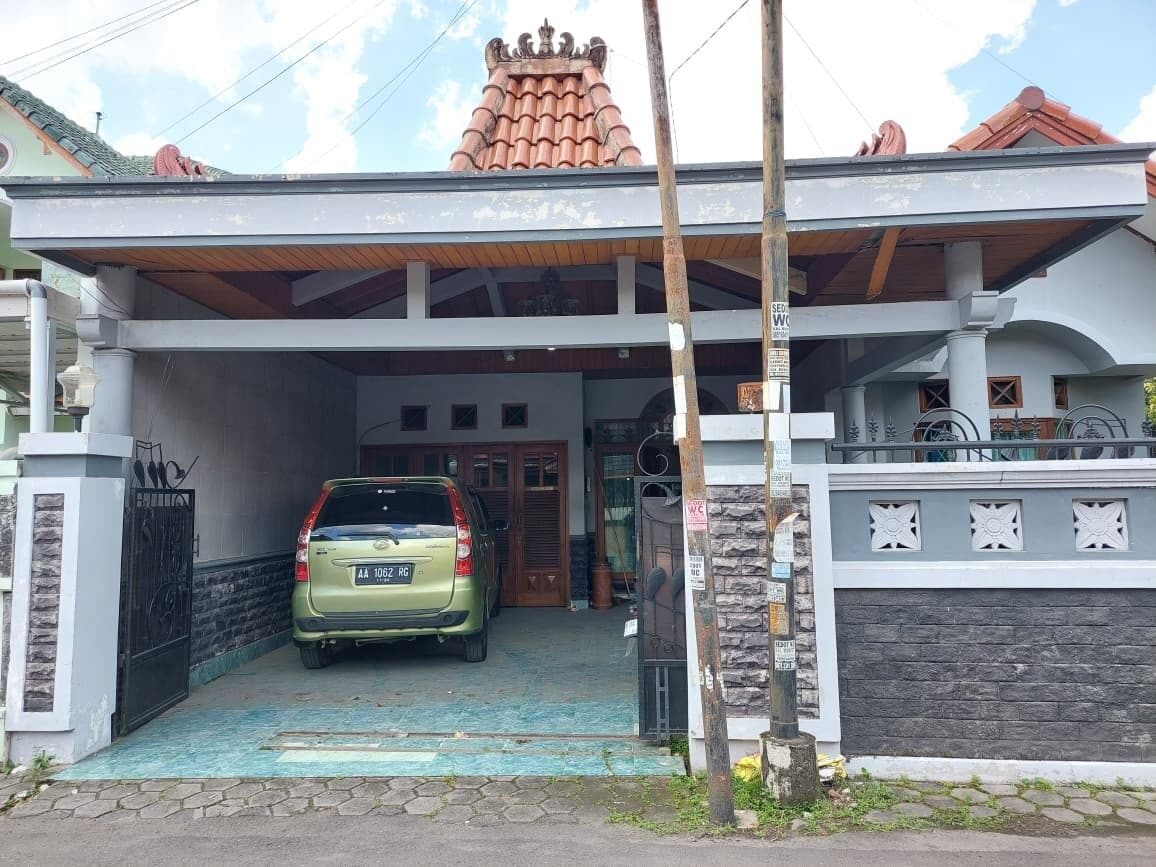 A two-story house with a covered driveway and a car parked inside.