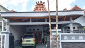 Una casa de dos pisos con un camino cubierto y un coche estacionado adentro.