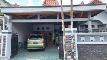 A two-story house with a covered driveway and a car parked inside.