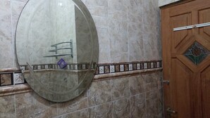 Un baño con un espejo grande, una puerta de madera y un muro con azulejos.
