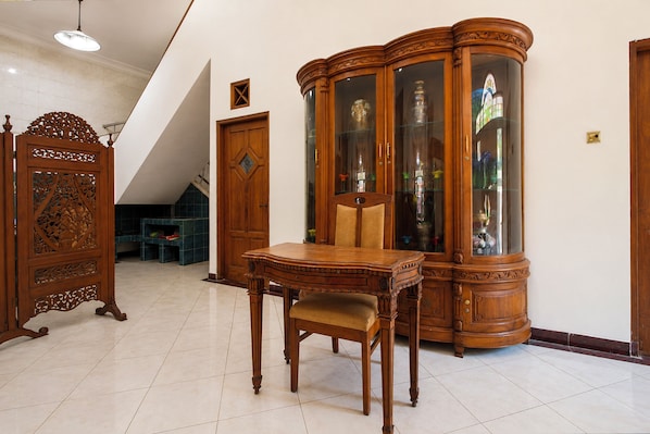 Un comedor con una mesa y sillas de madera, un aparador con puertas de vidrio y un separador decorativo de madera.
