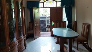 Una habitación con una mesa de comedor, sillas, un armario y una ventana con cortinas.