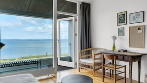 Habitació amb vista al mar, zona de dinar amb taula i cadires, i un sofà.