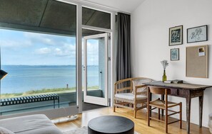 Ein Zimmer mit Meerblick, einem Essbereich mit Tisch und Stühlen sowie einer Couch.