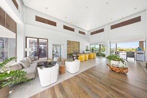 A spacious, modern lobby with a high ceiling, large windows, and a mix of seating areas including sofas and chairs. - Stylish Gold Coast 1BR  Near Beach  Pools & Gym (Noord)