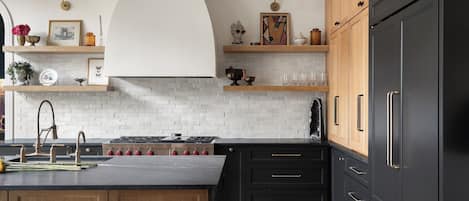 Une cuisine moderne dotée d’un îlot central, de meubles de rangement noirs et d’un sol à motifs en chevrons.