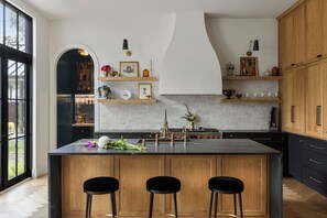 A modern kitchen with a central island, bar stools, and built-in shelving. - Award Winning. East Austin. Pool. Speakeasy. 1 mi from DT. Events & photoshoots (Austin)