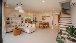Una sala moderna con sofá, una mesa de centro y un comedor con sillas de madera.