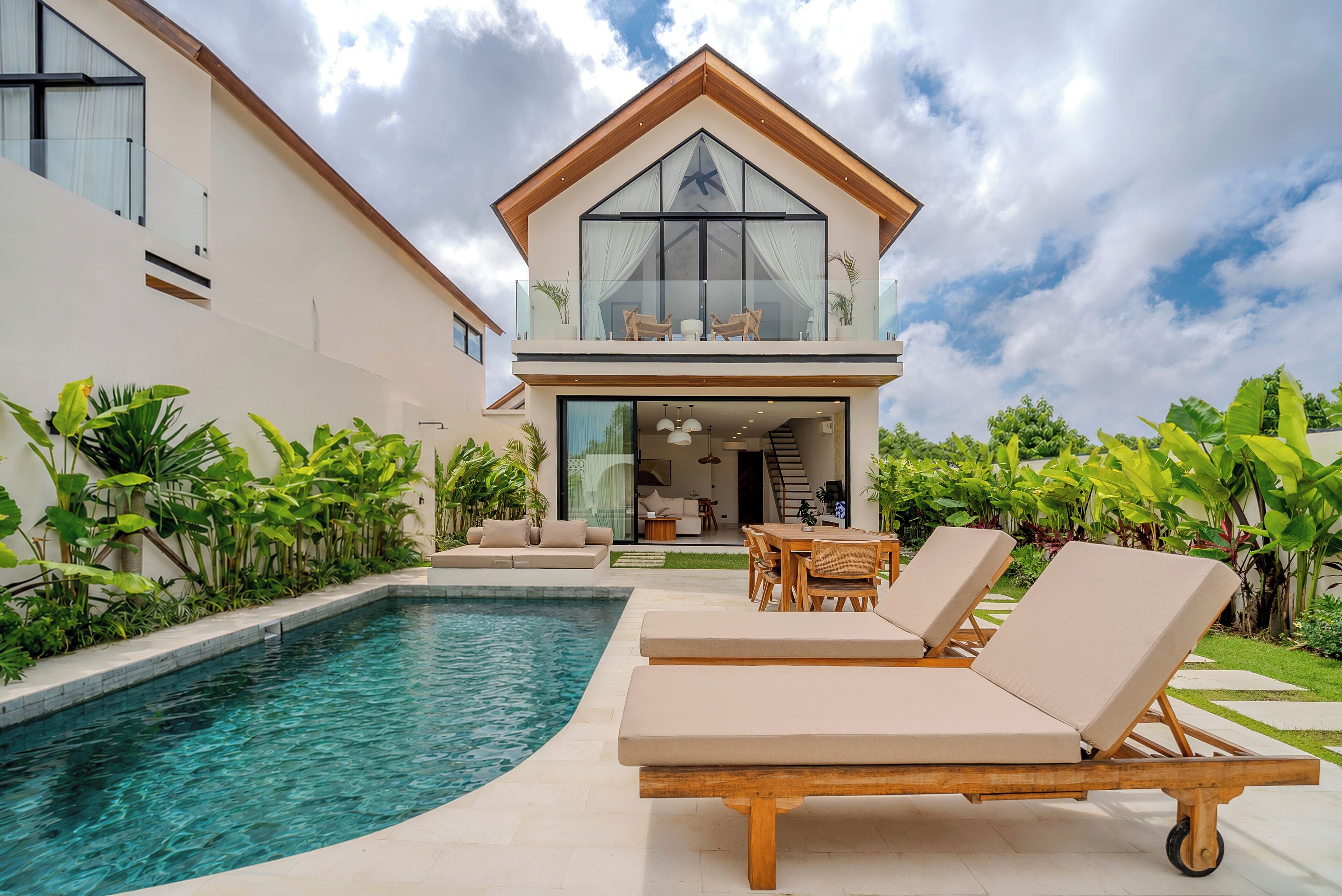 A modern house with a pool, lounge chairs, and a well-maintained garden.