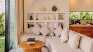 Una sala de estar moderna con un sofá seccional, una mesa de centro de madera y un estante montado en la pared con jarrones decorativos.